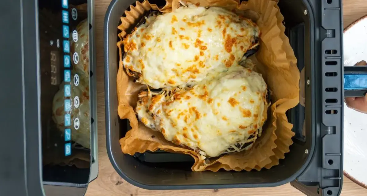 Dos mitades de berenjenas gratinadas con queso fundido, listas para disfrutar, recién salidas de la freidora de aire.