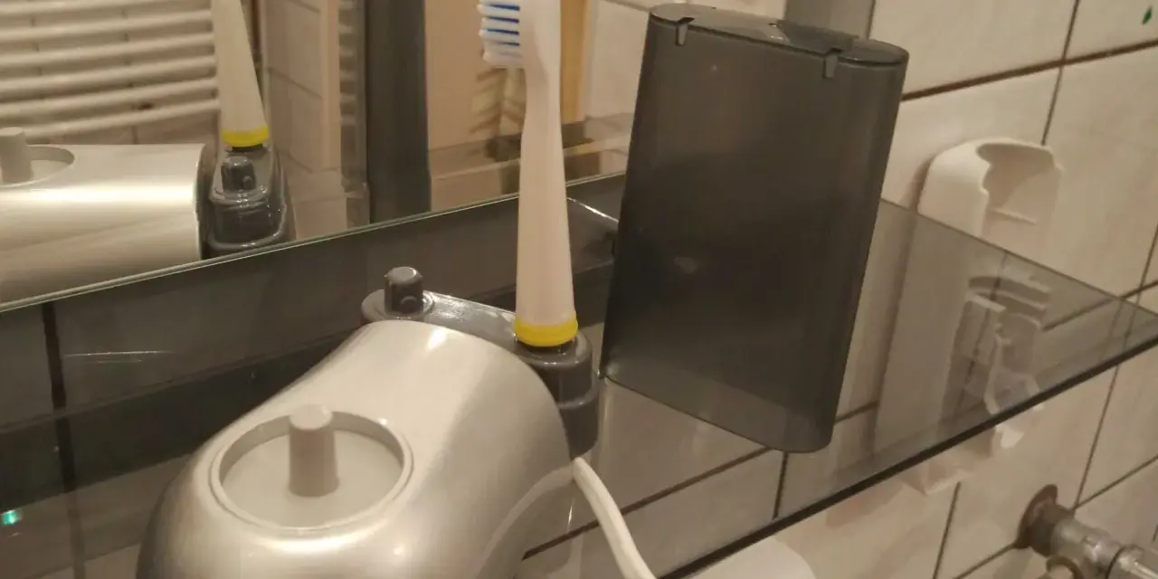 Pierwsze ładowanie szczoteczki elektrycznej. Nowa szczoteczka z ładowarką i etui na półce w łazience.