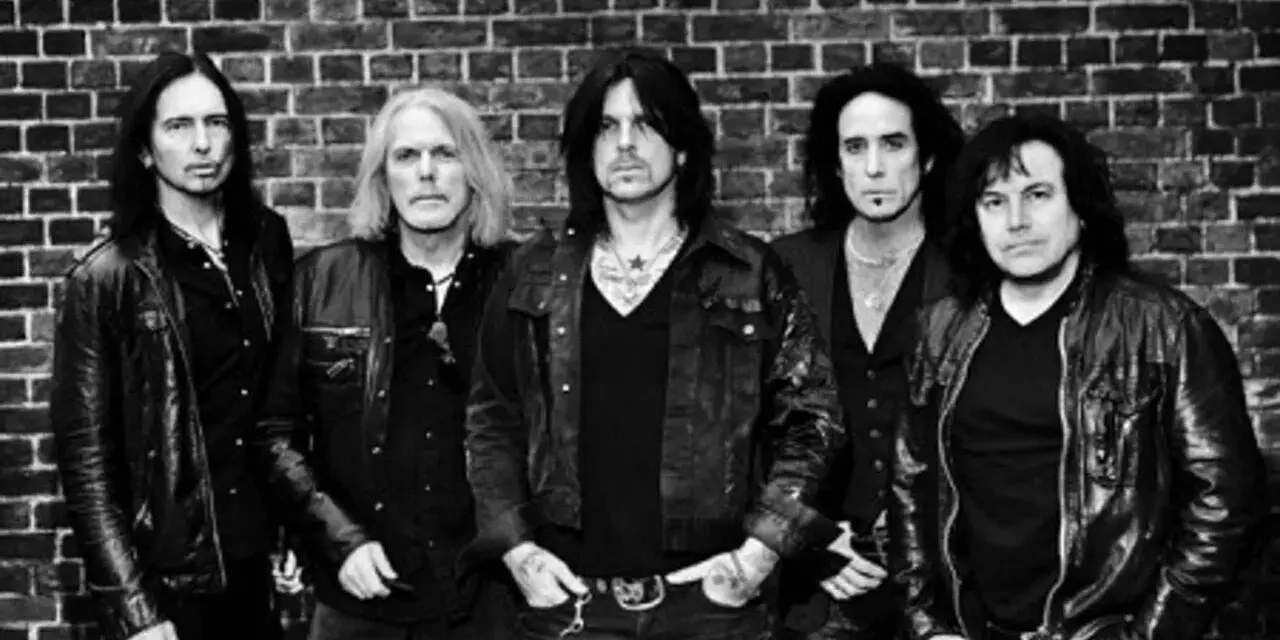 Les membres de Black Star Riders posent devant un mur de briques.