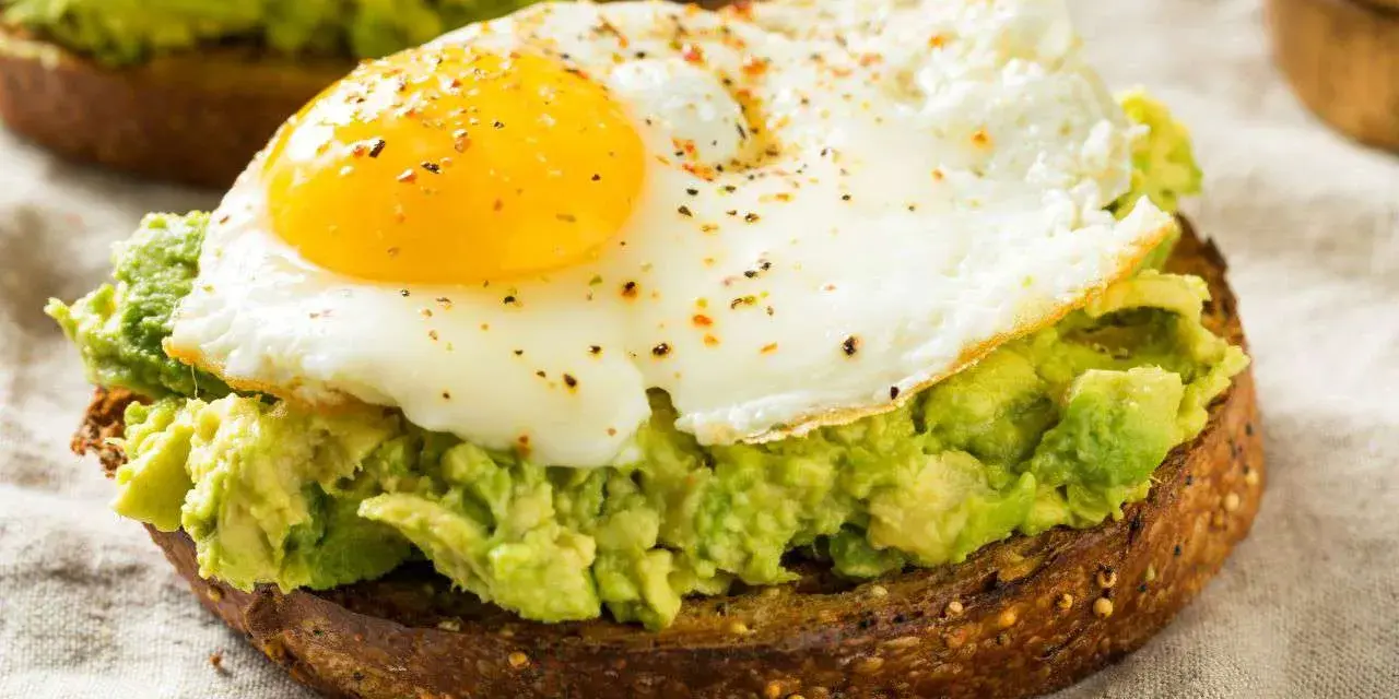 Tostada integral con aguacate machacado y huevo frito, un delicioso desayuno keto.