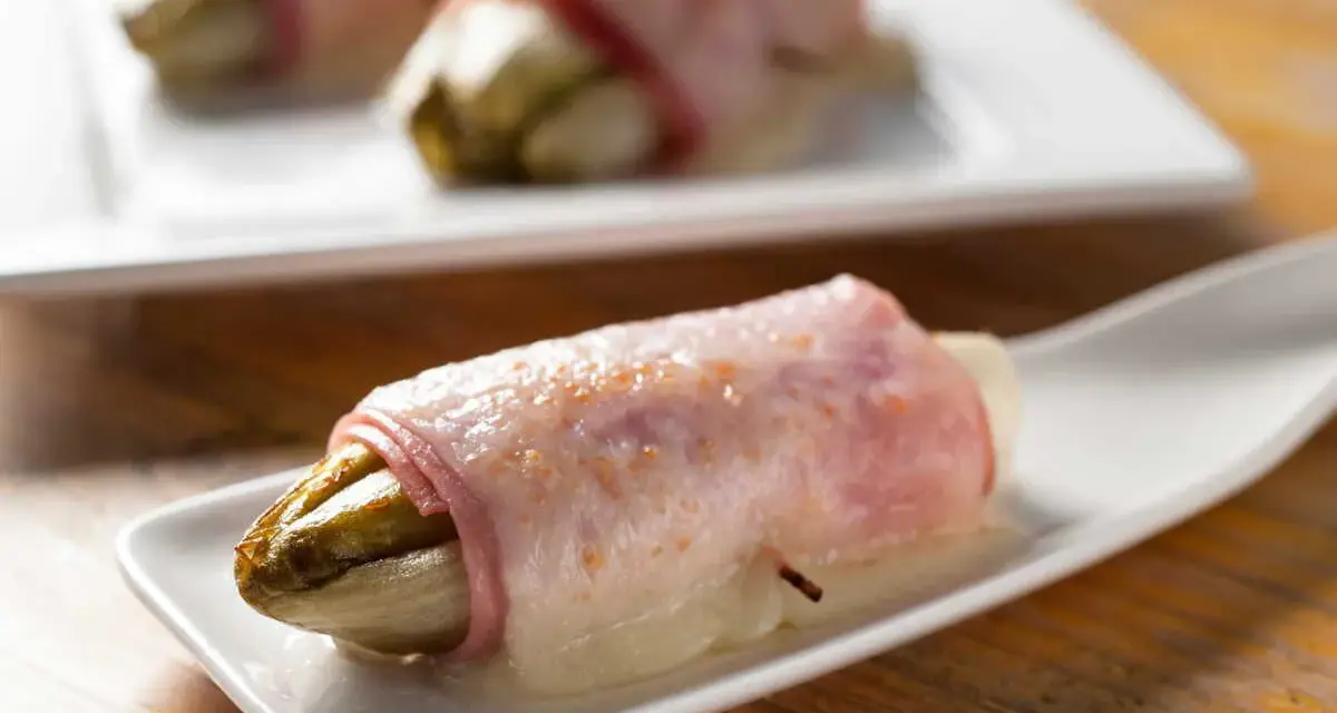 Endives au jambon sans béchamel, une recette simple et savoureuse. L'endive fondante enroulée de jambon sur une cuillère blanche.