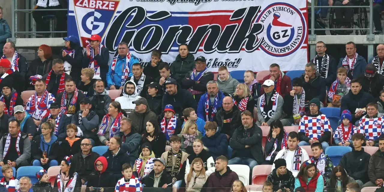 Tłum kibiców Górnika Zabrze, w szalikach i barwach klubowych, wspiera drużynę.