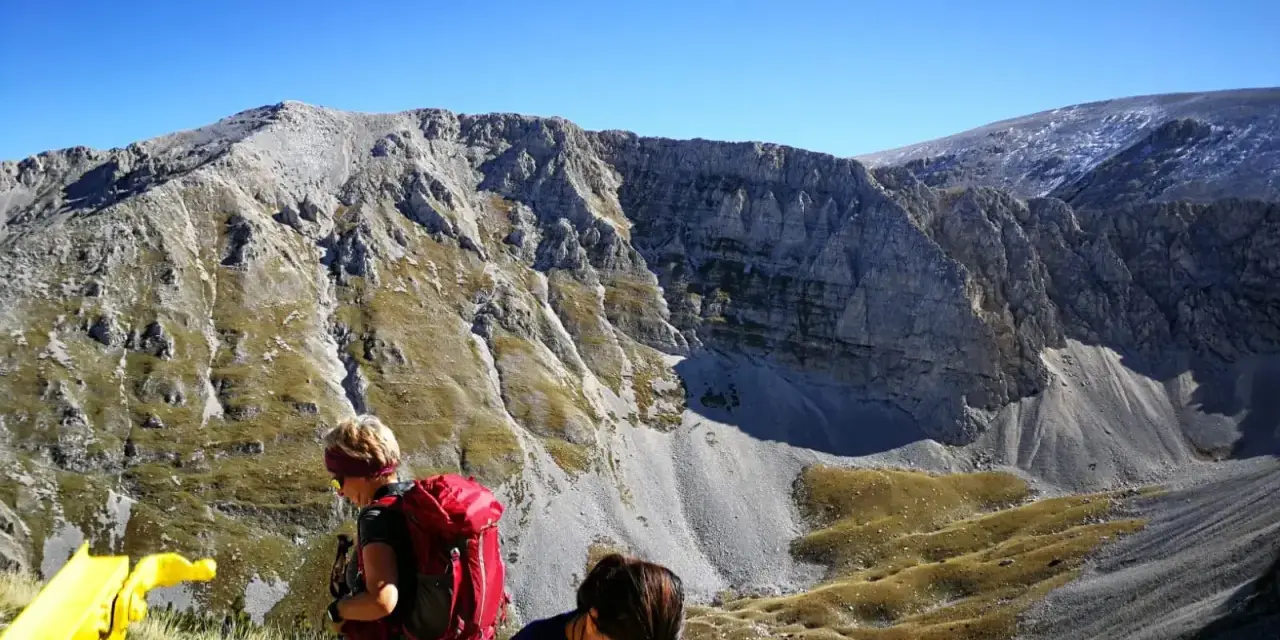 Escursionisti con zaini rossi ammirano il panorama montuoso vicino al bivacco Fusco.