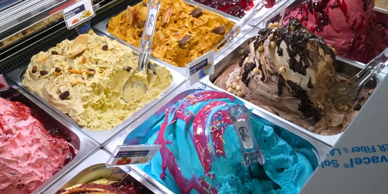 Verschiedene Sorten Eis: Pistazie, Karamell, Beeren, Schoko-Nuss und ein blaues Eis mit bunten Streuseln. Ein Fest für die Sinne!