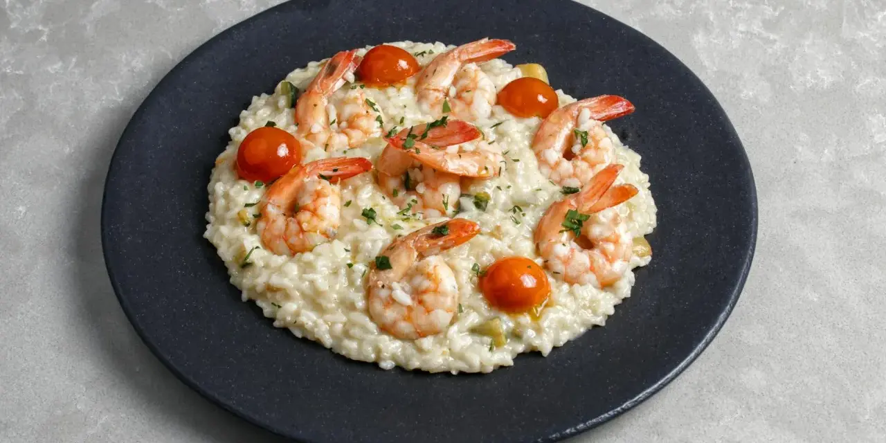 Kremowe risotto z krewetkami i pomidorkami koktajlowymi, posypane natką pietruszki. Idealny przepis na risotto dla każdego.