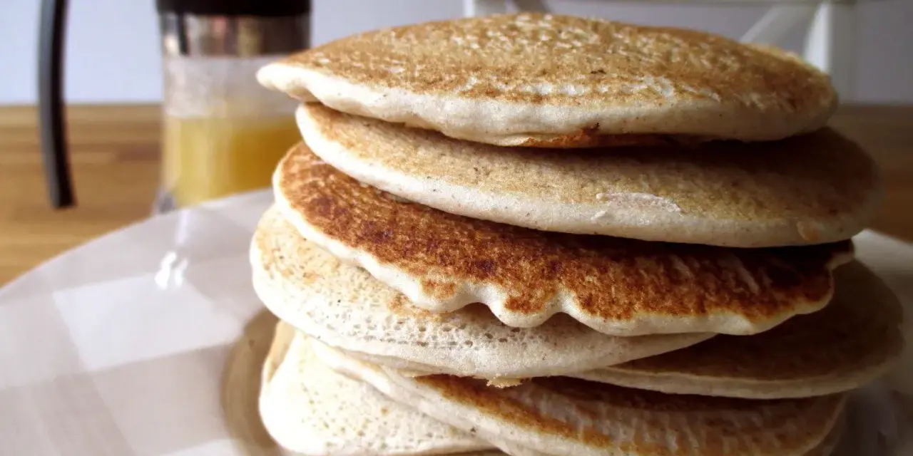 Pila di soffici pancake con farina di avena, dorati e invitanti, pronti per una colazione sana e gustosa.