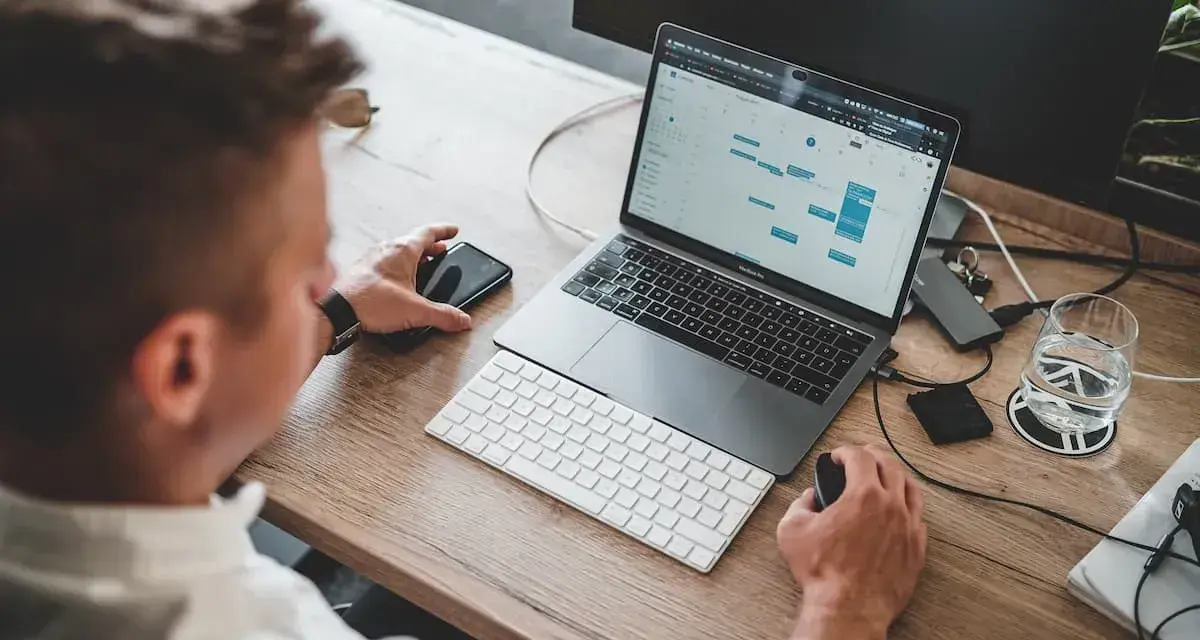 Mężczyzna pracuje przy laptopie, planując zadania. To idealne miejsce do nauki, by rozpocząć kurs spedytora i zdobyć nowe umiejętności.