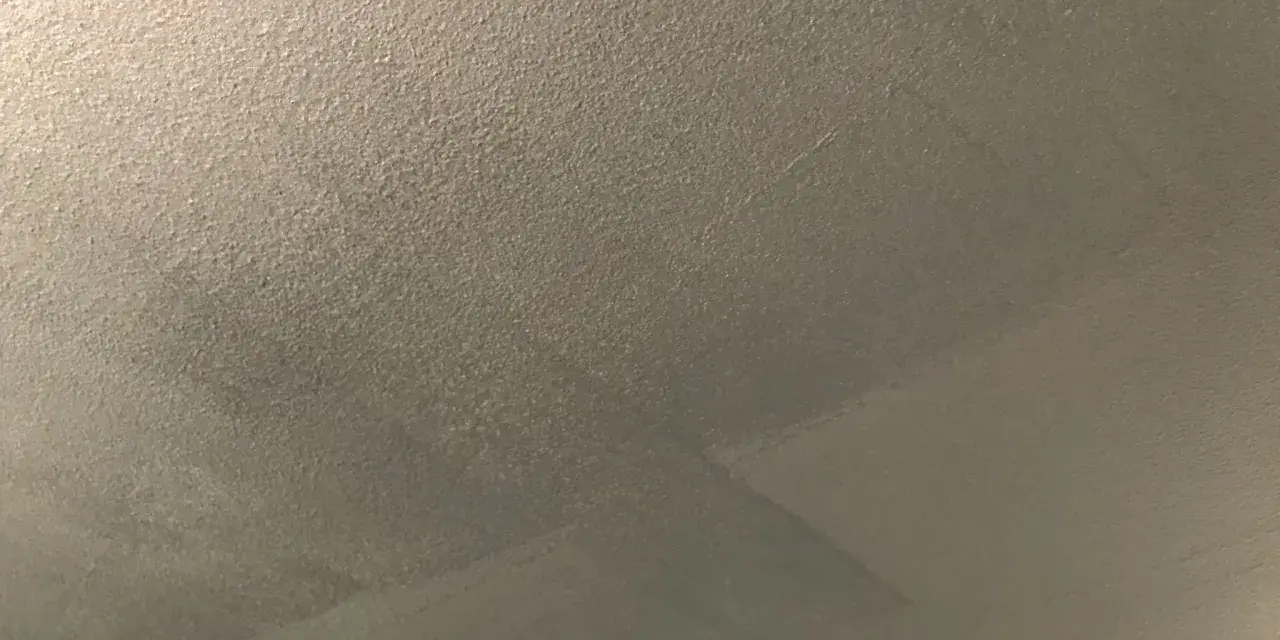Ett flammigt tak efter målning, med synliga penseldrag och en textur som påminner om sand.