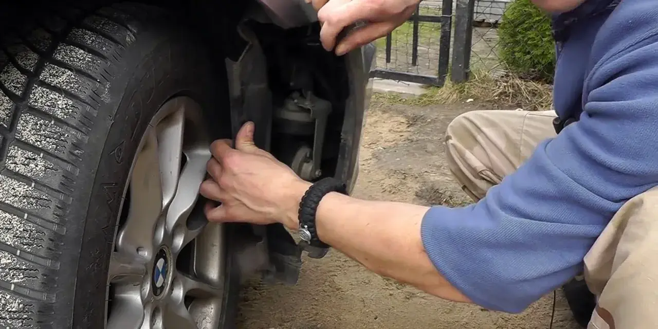 Naprawa awarii PDC BMW. Mężczyzna demontuje fragment nadkola, by dostać się do czujników parkowania.
