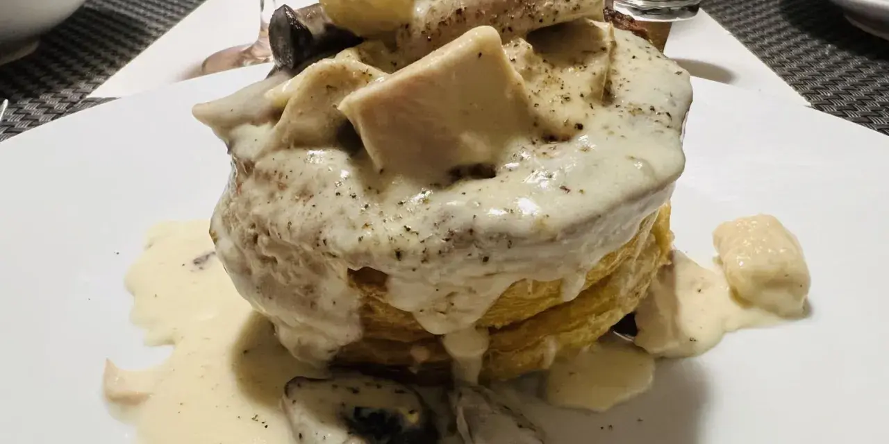 Une bouchée à la reine rapide, garnie de poulet, champignons et d'une sauce crémeuse, servie sur une pâte feuilletée dorée.