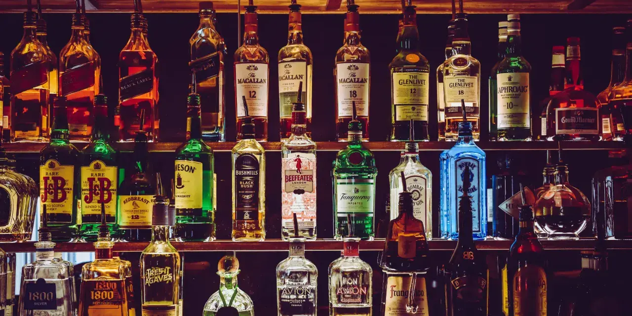 Półki pełne alkoholi, w tym butelki z napisem "The Macallan" i "The Glenlivet", sugerujące najlepsza polska whisky.