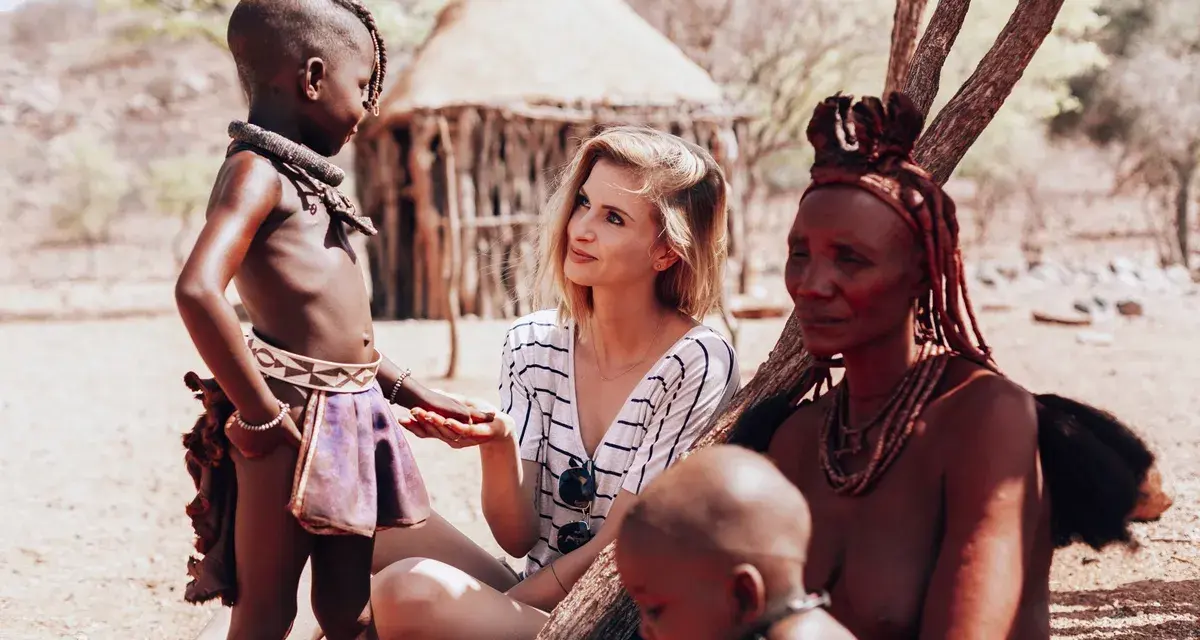 Ludzie Himba w Namibii: młoda kobieta rozmawia z dzieckiem i starszą kobietą w tradycyjnych strojach.