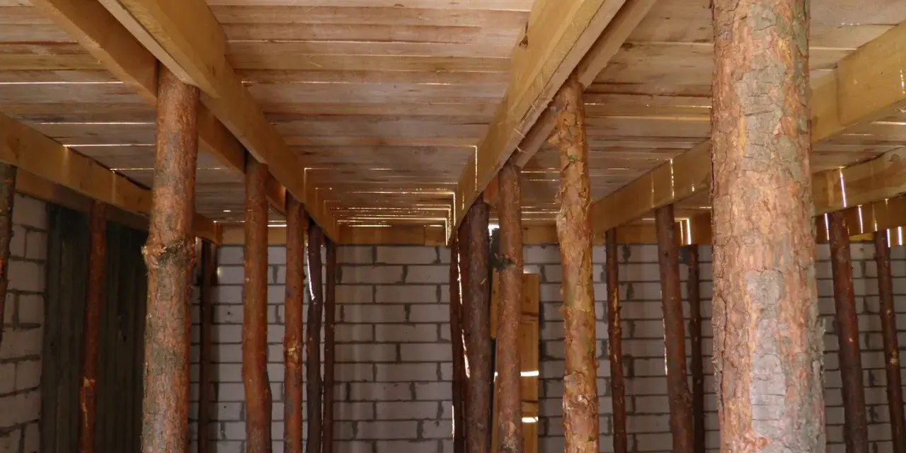 Szalowanie stropu z drewnianymi stemplami, tworzącymi rusztowanie pod przyszły strop.