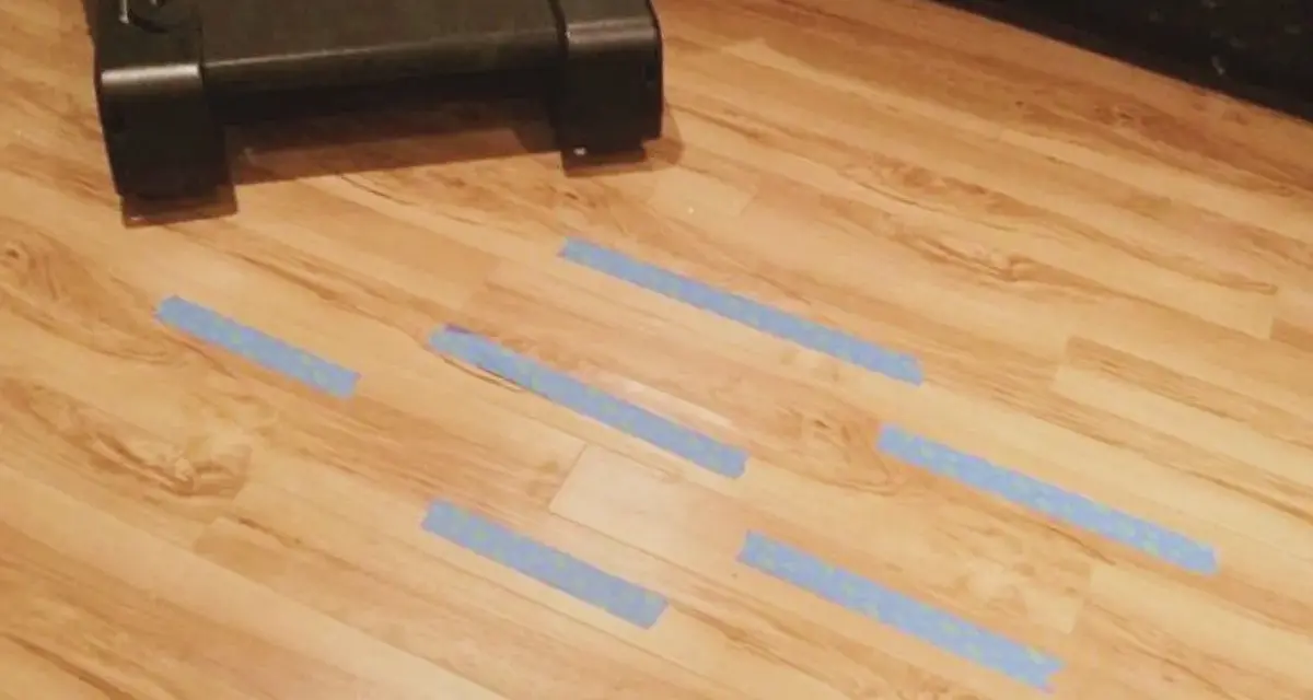 Marcando con cinta azul las tablas de tarima flotante levantadas por humedad para repararlas.