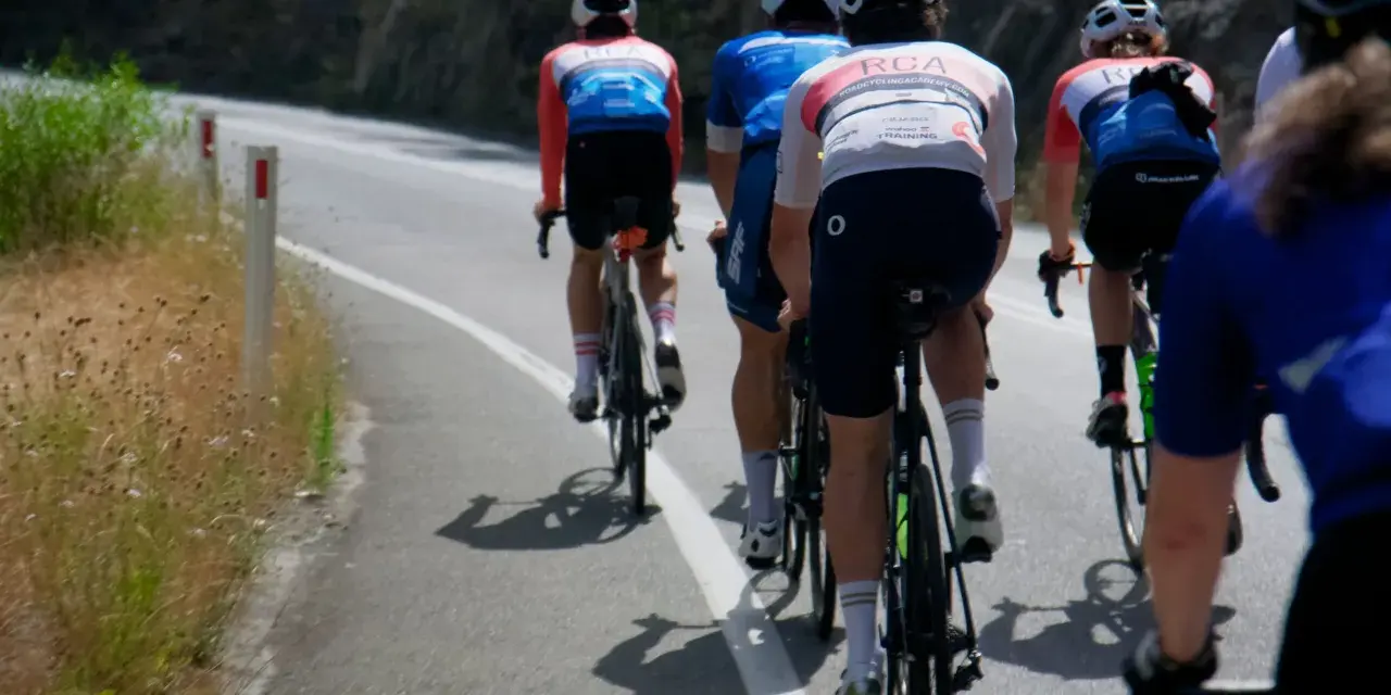 Cyclists in racing gear tackle a steep road, their shadows stretching long on the asphalt. This is the essence of category climbs cycling.