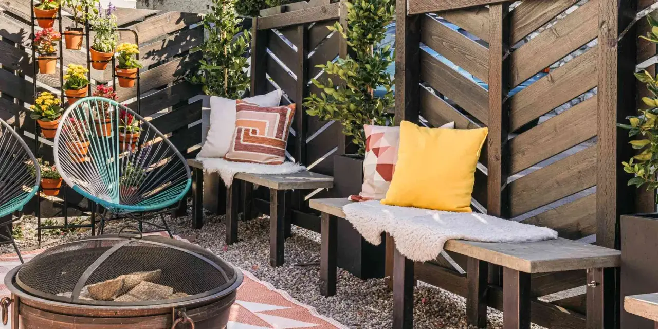 A cozy patio with a diy privacy screen, fire pit, and colorful chairs.