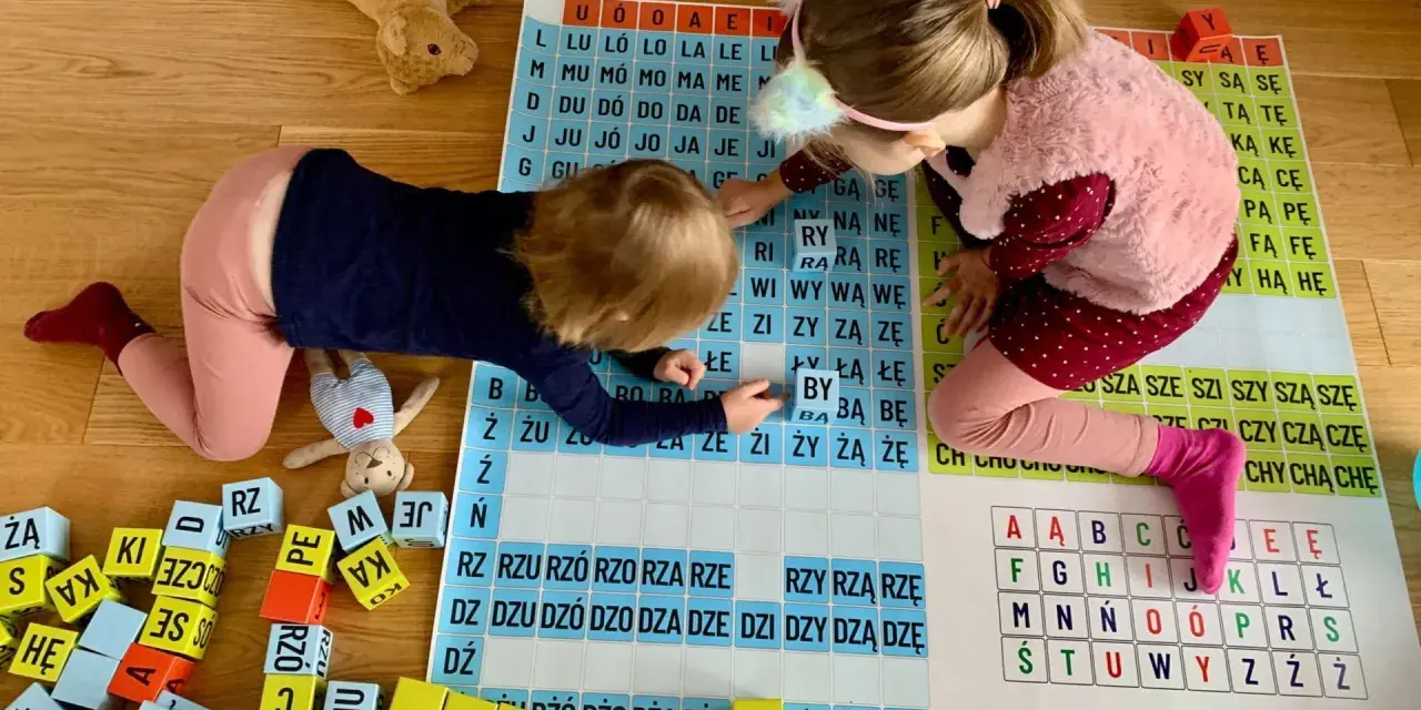Dwie dziewczynki uczą się czytać, układając litery na planszy. Zabawa z literami to świetny sposób, jak nauczyć dziecko czytać.