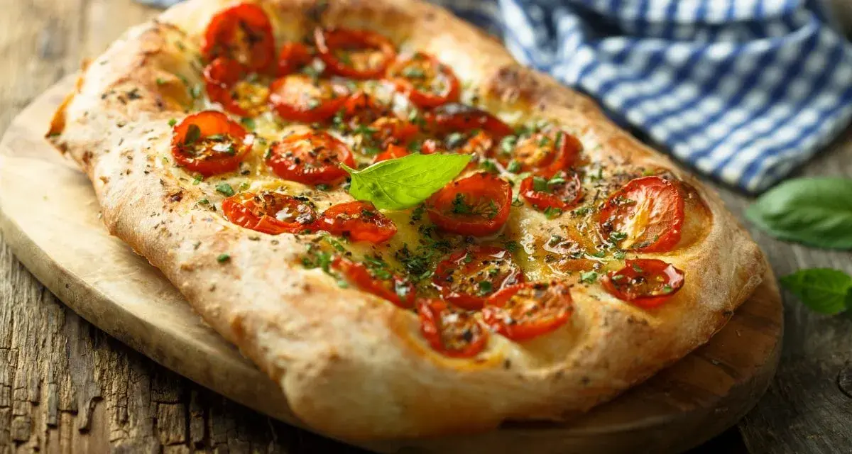 Pyszna focaccia z pomidorkami koktajlowymi i bazylią. Idealna jako dodatek do dań lub samodzielna przekąska. Z czym jeść focaccię? Z wszystkim, co lubisz!