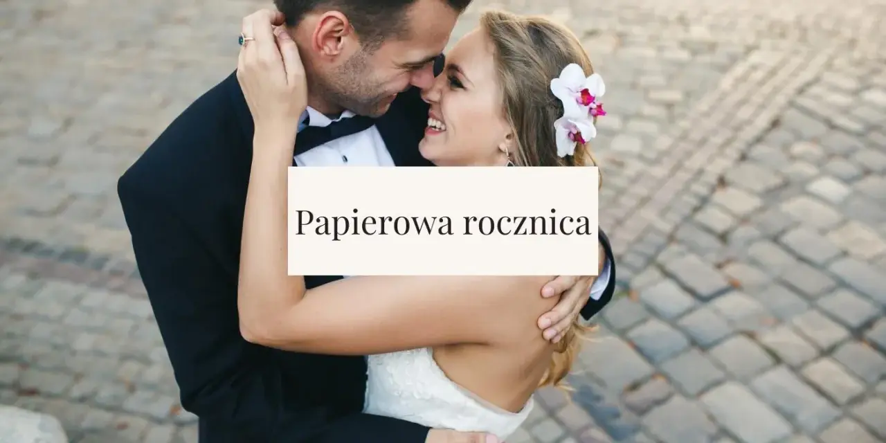 Para świętuje papierową rocznicę ślubu. Uśmiechnięci, w objęciach, z kwiatem we włosach panny młodej.