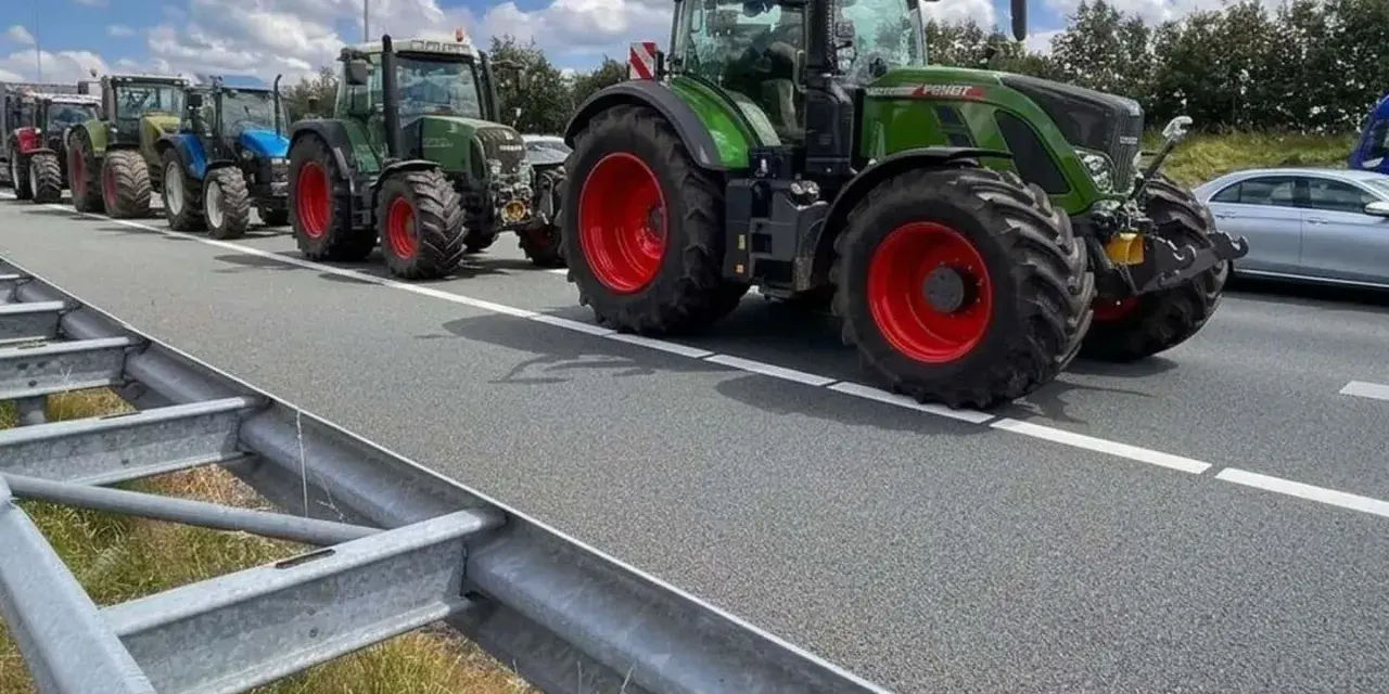 Una fila di trattori attraversa un'autostrada, un'immagine che ricorda che sulle autostrade e strade extraurbane principali è vietata la circolazione di macchine agricole.