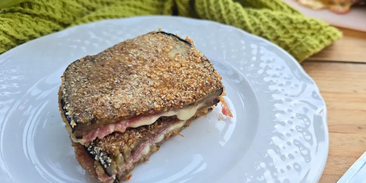 Un goloso cordon bleu di melanzane, impanato e fritto, con un cuore filante di formaggio e prosciutto.