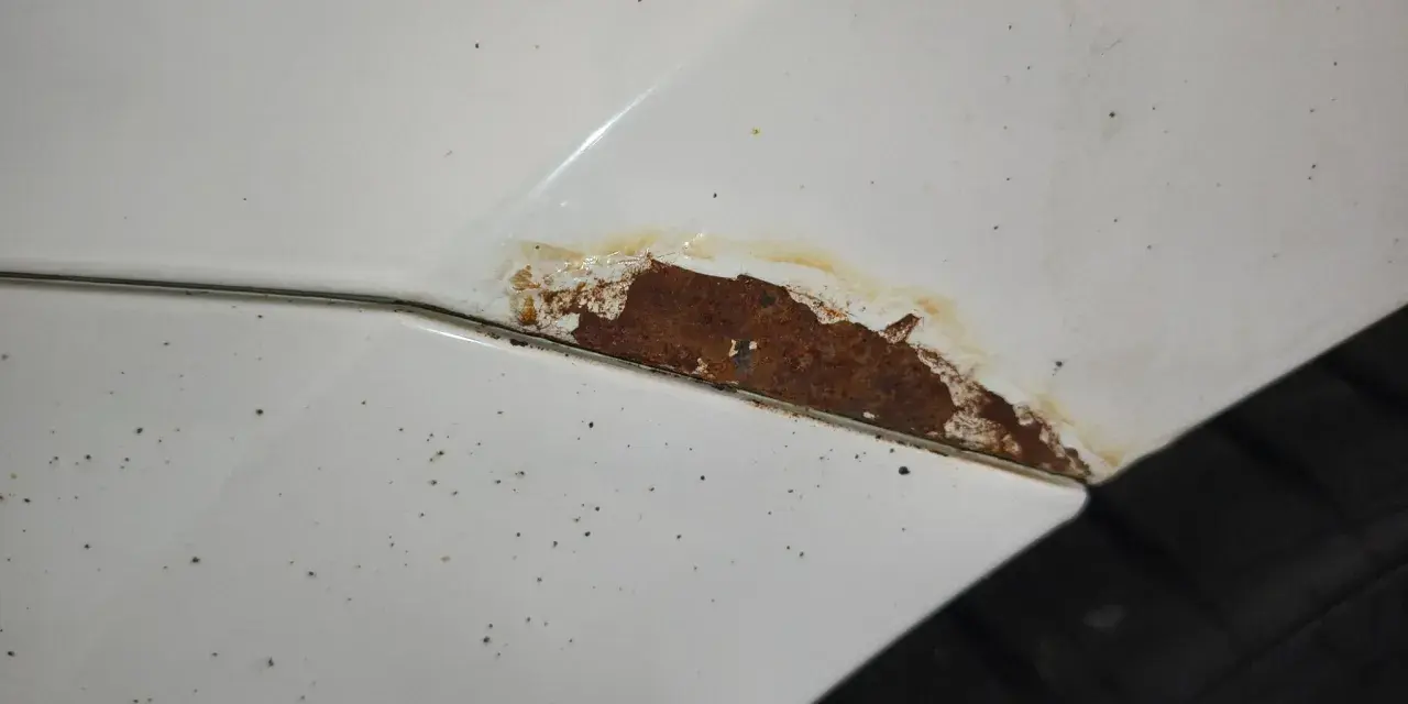 Rostfläckar på vit bil, dags att slipa rost innan det blir värre.