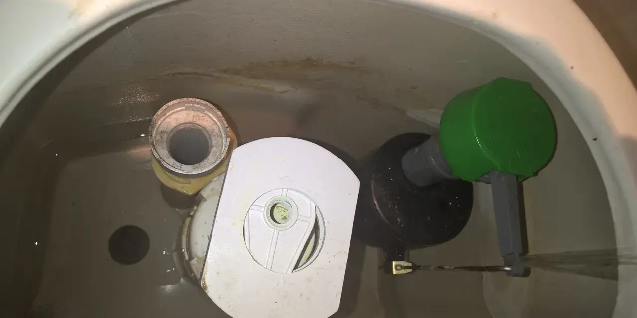 Insidan av en toalettcistern med en Gustavsberg Nordic 2002-mekanism. Vatten rinner ner från flottören.