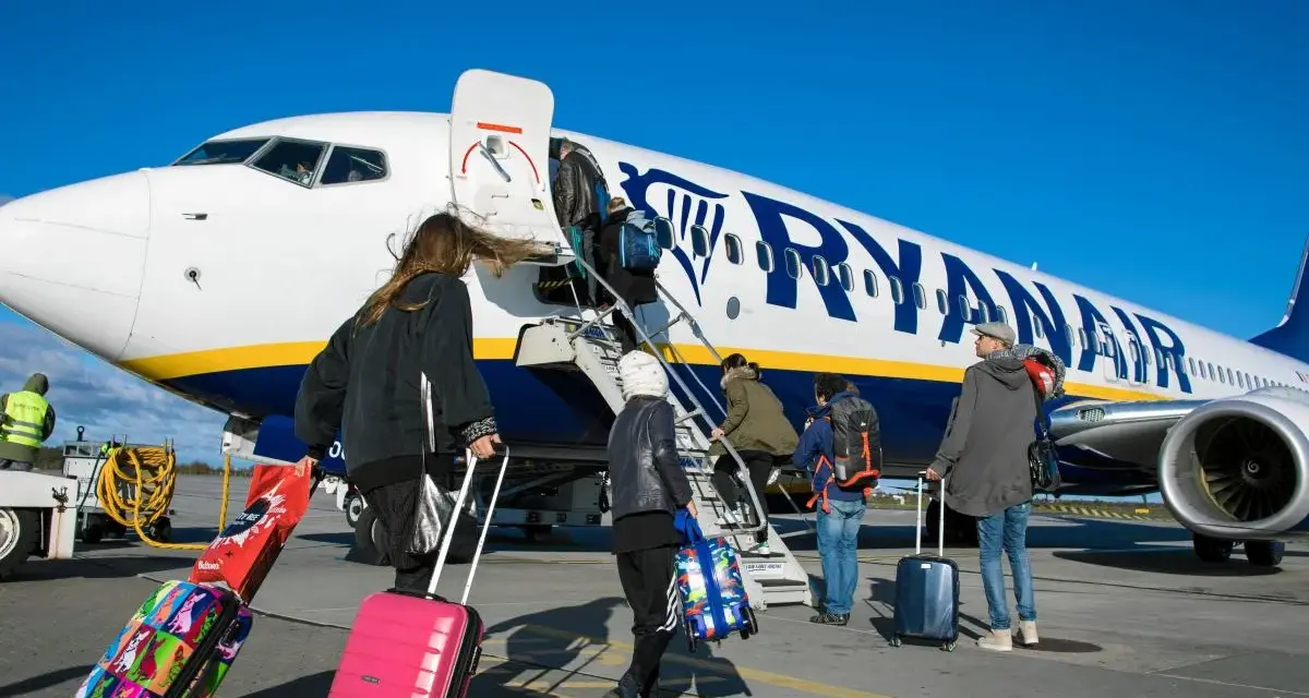 Ludzie z bagażami wsiadają do samolotu Ryanair. Może to być początek podróży lub sytuacja, gdy ktoś planuje **Ryanair zwrot biletu**.