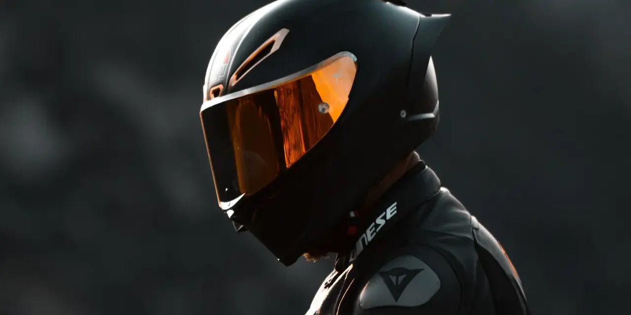 Casco nero lucido con visiera arancione riflettente, pronto per un giro in moto.