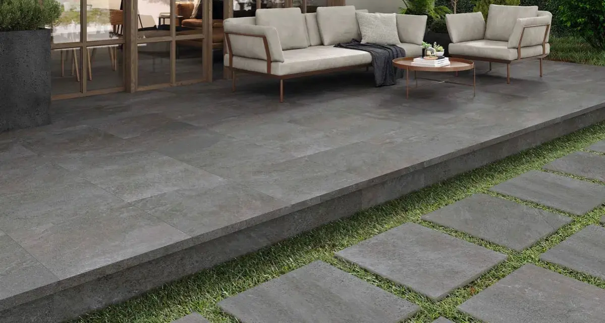 Terraza moderna con suelo de baldosas grises, ideal para saber como poner baldosas en suelo de tierra. Sofá y sillones invitan al descanso.