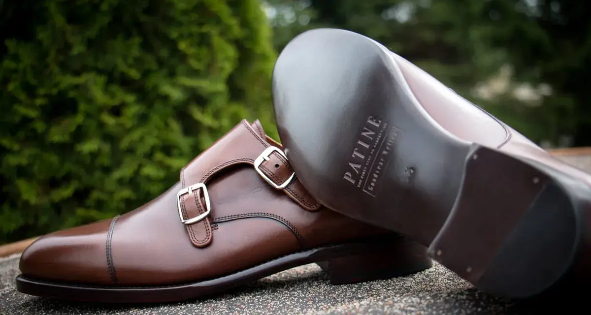 Eleganckie brązowe buty z podwójnymi klamrami, wykonane z wysokiej jakości kruponu. Widoczna podeszwa z logo marki.