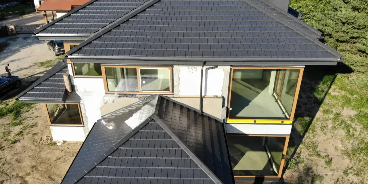 Nowy, ciemny dach z dachówki ceramicznej. Zastanawiasz się, ile kosztuje wymiana pokrycia dachowego?