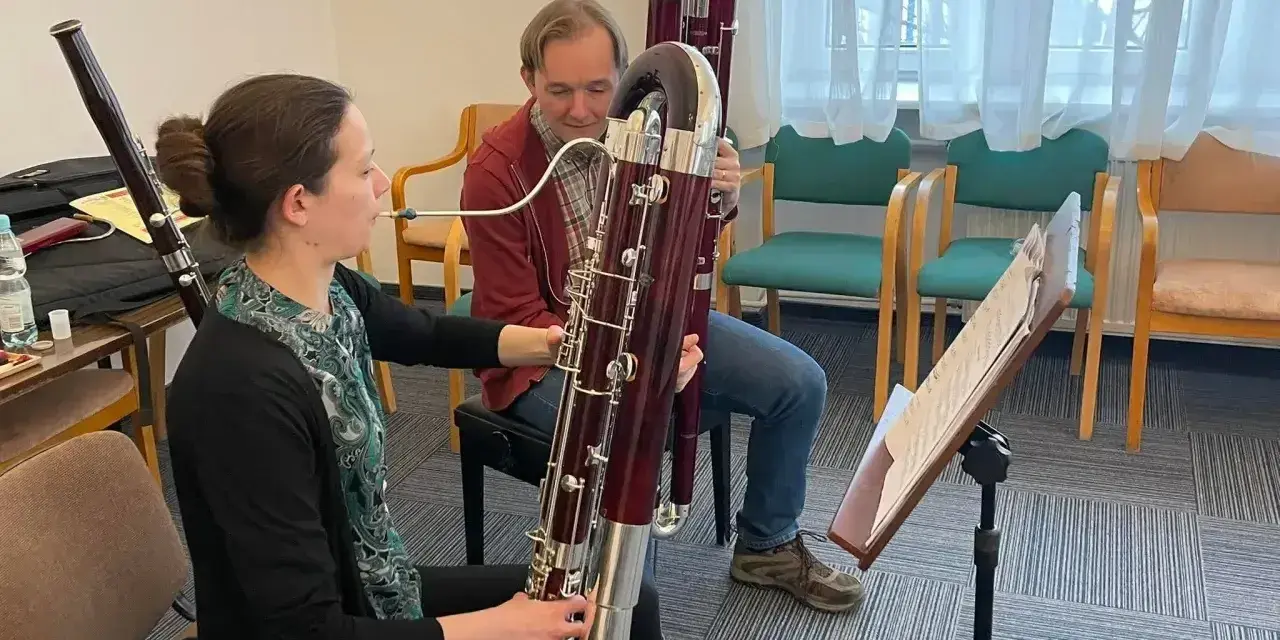 Kobieta i mężczyzna ćwiczą grę na fagotach. Jaki to instrument? Dwa duże, drewniane instrumenty dęte drewniane, fagot, są w centrum uwagi.