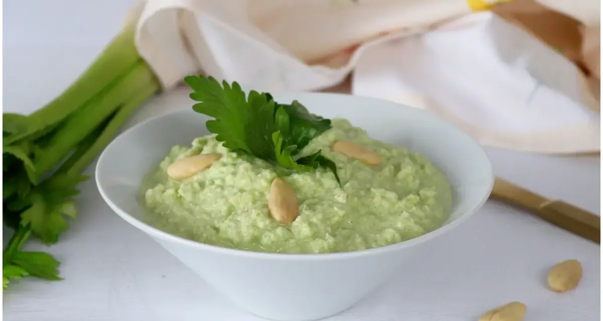 Pesto di sedano fresco, guarnito con mandorle e prezzemolo, pronto per essere gustato.