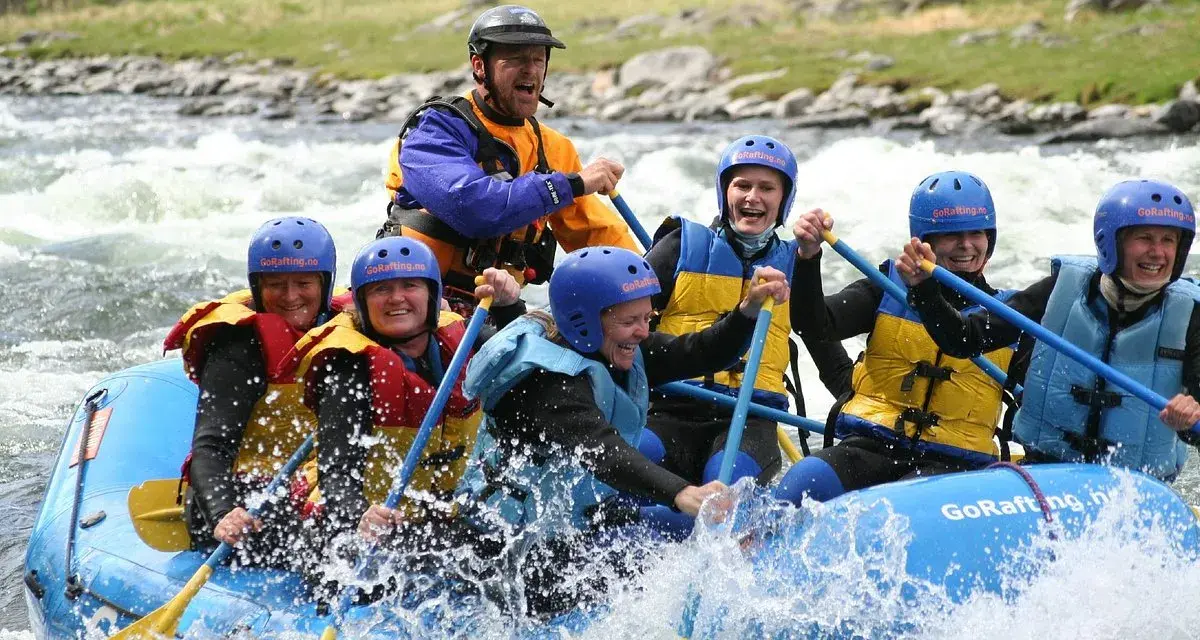 Glada människor i en flotte på forsigtigt vatten, redo för sjoa rafting.