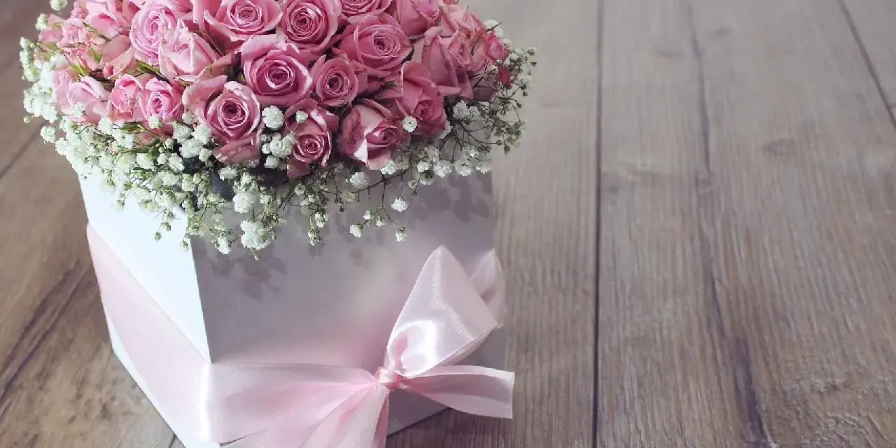 Piękne różowe róże w białym pudełku z różową wstążką. Idealne na prezent, pokazują, jak zrobić pudełko do flower box.