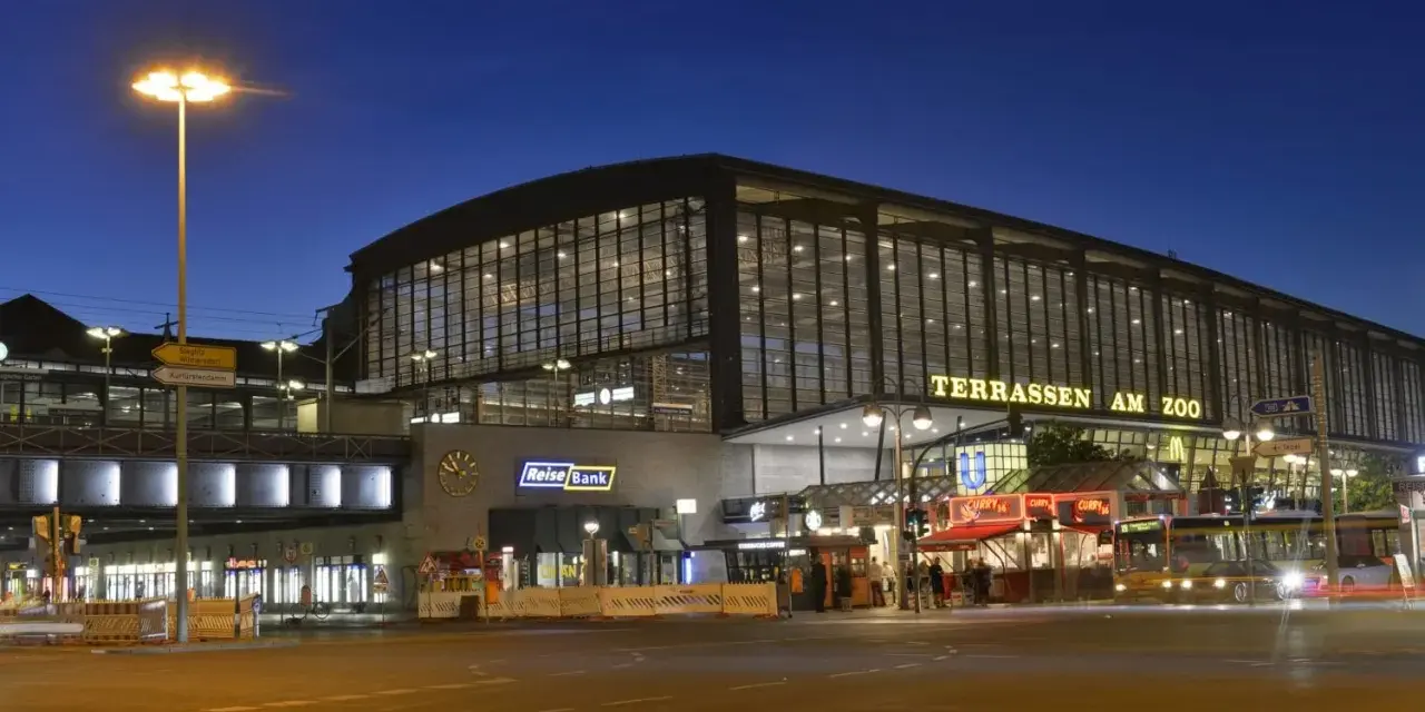 Der Bahnhof Zoo in Berlin bei Nacht. Die beleuchteten Terrassen am Zoo erstrahlen im Dunkeln.