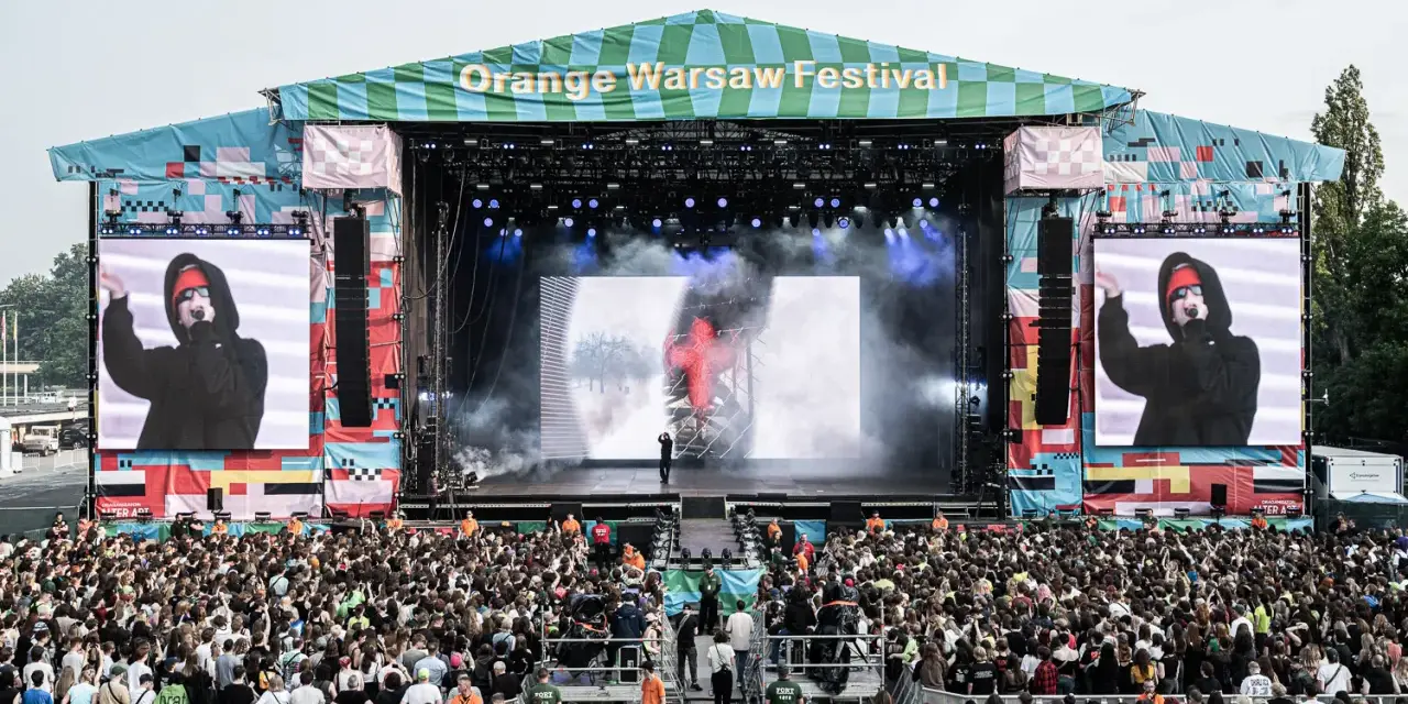 Tłum ludzi na Orange Warsaw Festival 2026, scena z artystą na ekranie i dymem.
