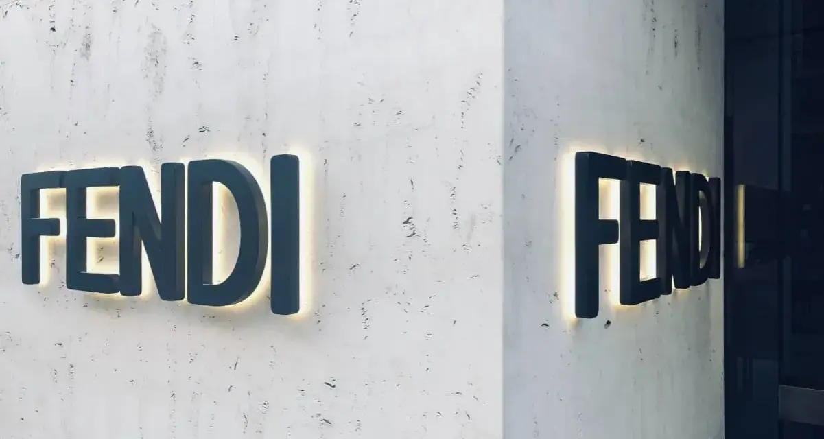 Insegna luminosa Fendi su una parete di marmo. Il **Fendi significato** è lusso e artigianalità italiana.