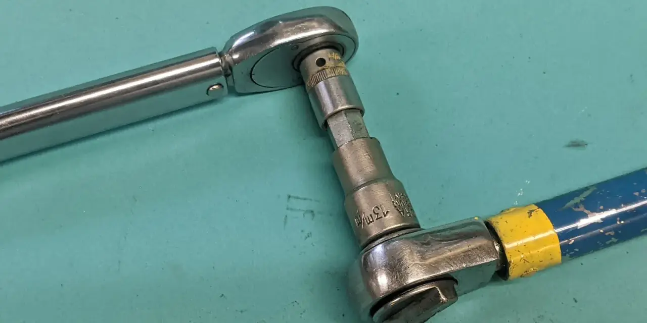 Två verktyg kopplade för att kalibrera momentnyckel. En momentnyckel i metall och en blå/gul skruvdragare med hylsa.