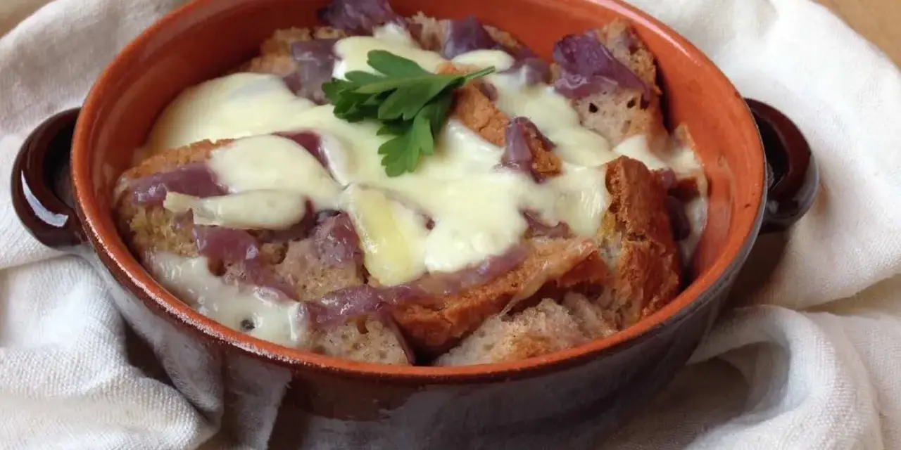 Zuppa di cipolle toscana fumante, con crostini dorati e formaggio filante, guarnita con prezzemolo fresco.