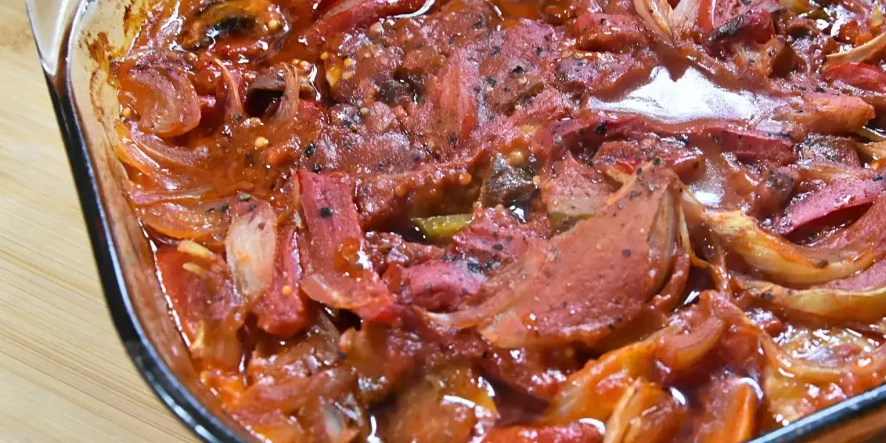 Pyszna karkówka po cygańsku w sosie pomidorowym z cebulą i papryką, zapiekana w szklanym naczyniu.