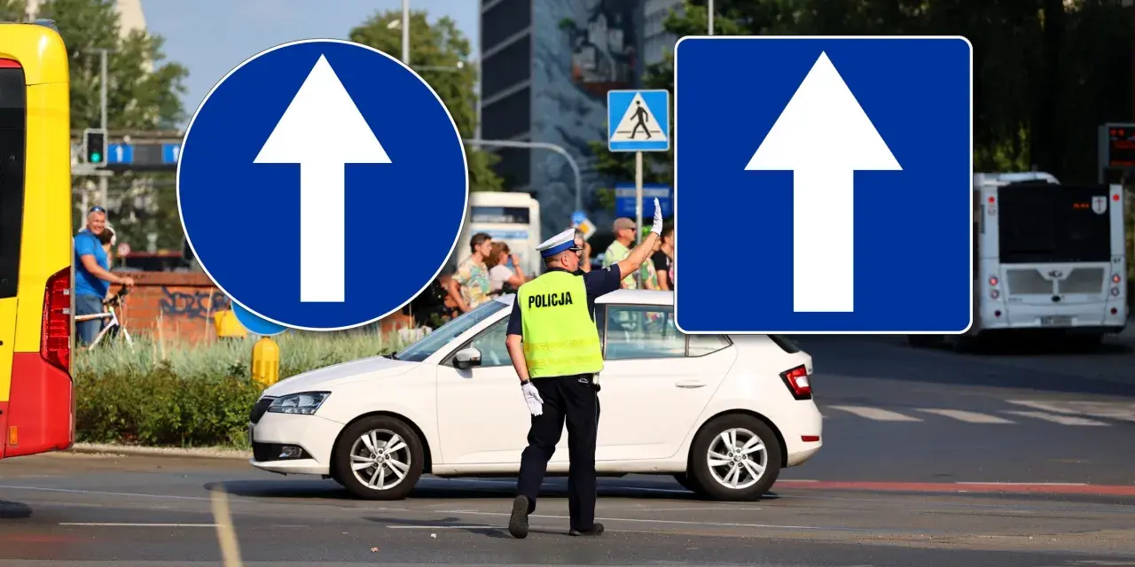 Policjant kieruje ruchem przy znakach droga jednokierunkowa. Biała Skoda czeka na sygnał.