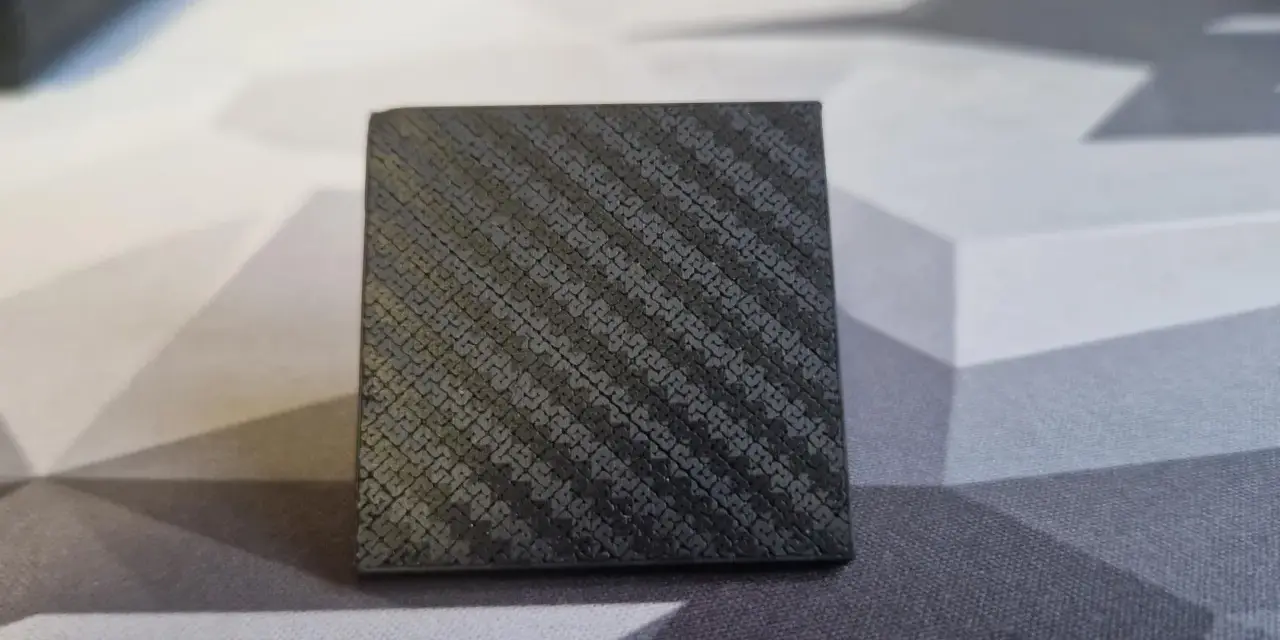 A small cube with a textured surface, showcasing the intricate pattern achieved through carbon fiber 3D printing.