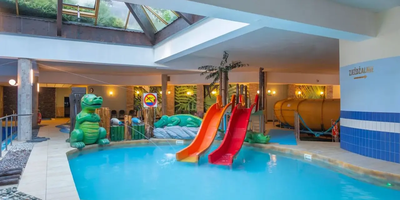 Karpacz hotel z basenem i atrakcjami dla dzieci: zjeżdżalnie, basen, zielone dinozaury i tropikalne dekoracje.