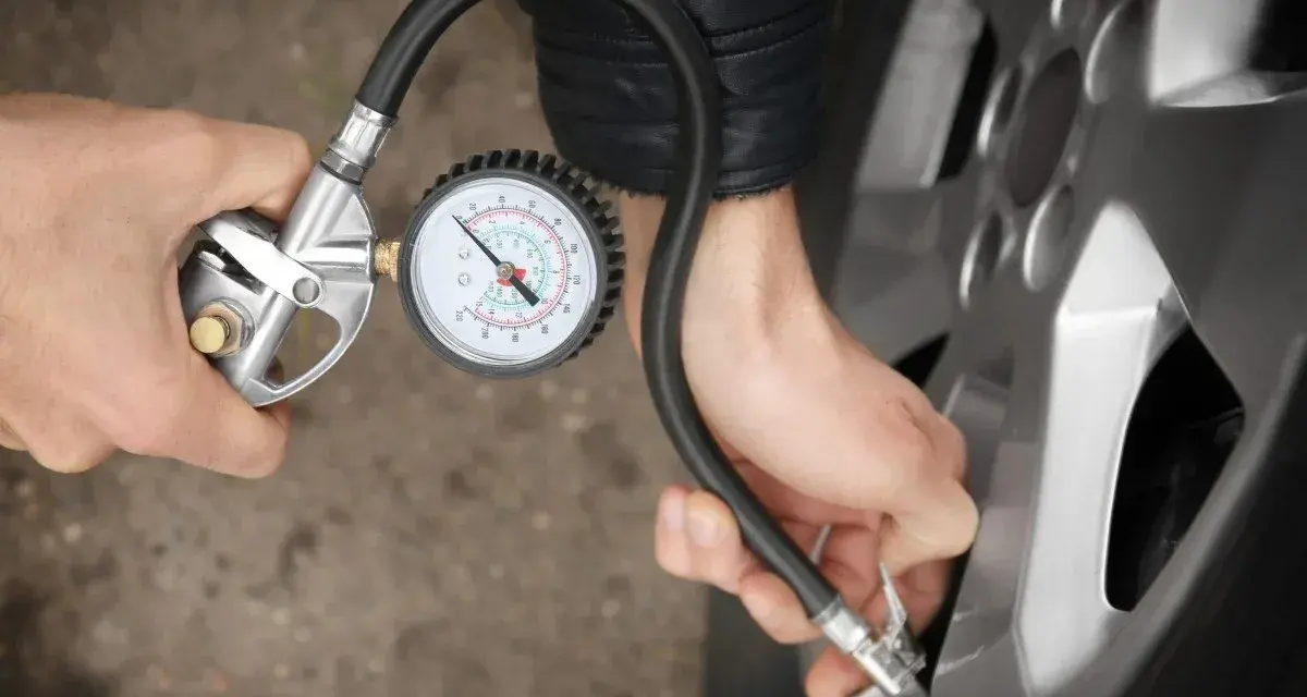 Person prüft den Reifendruck mit einem Manometer. Die warmen Reifen sind wichtig für die Sicherheit.
