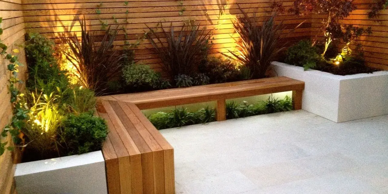 Elegante decoracion patio interior con banco de madera y plantas iluminadas.