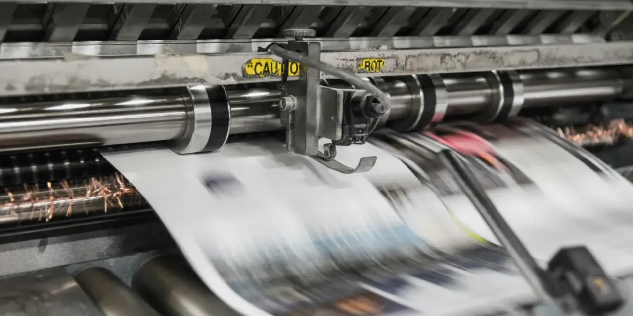 Maszyna drukarska w ruchu, tworząca strony gazet metodą wklęsłą lub offsetową.