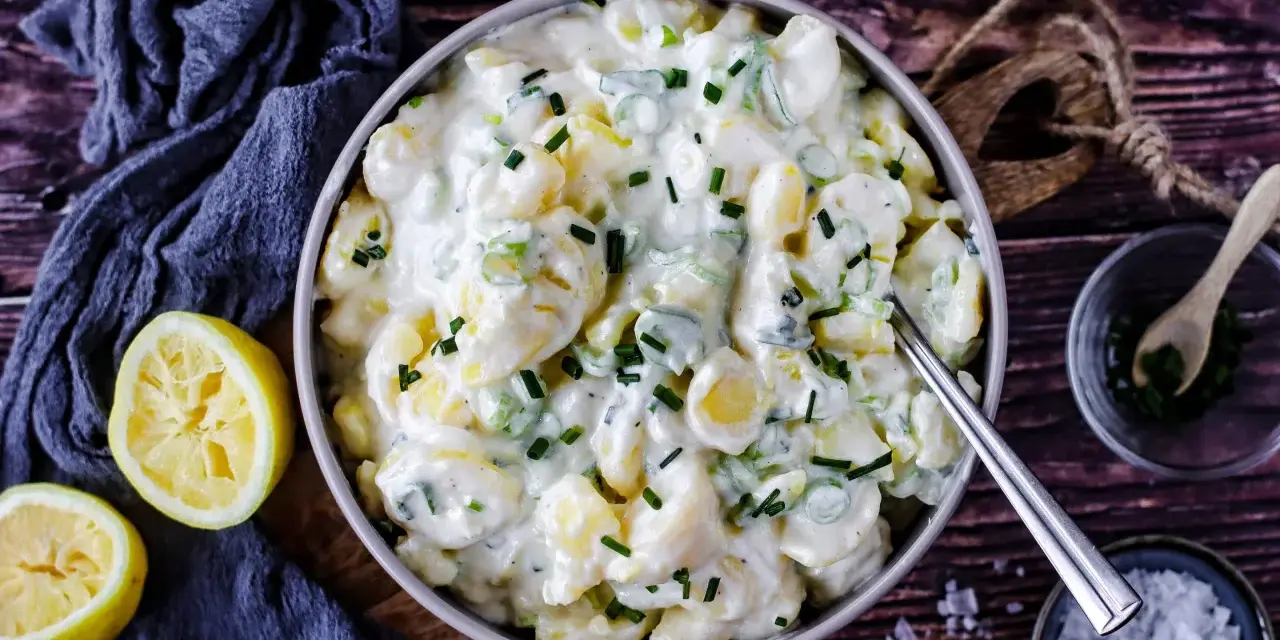 Cremiger Kartoffelsalat mit Joghurt, garniert mit Schnittlauch. Dazu passen frische Zitronenspalten.