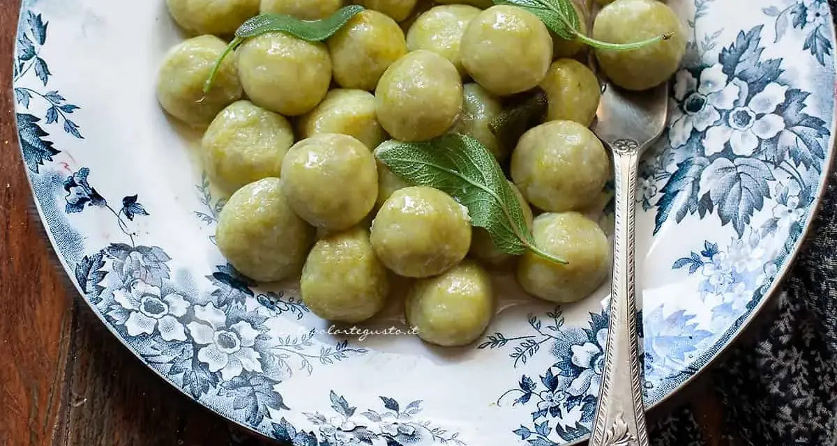 Gnocchi di zucchine morbidi e profumati, guarniti con foglie di salvia fresca su un piatto decorato.